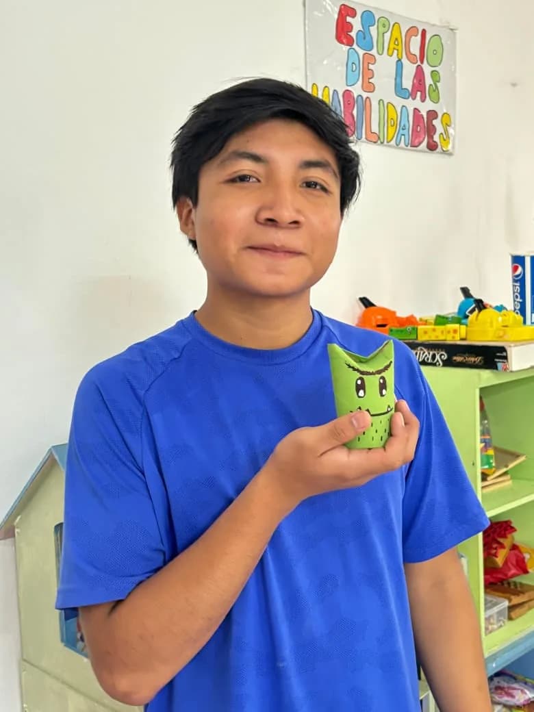 Un joven muestra la figura de cartón que decoró en el taller.