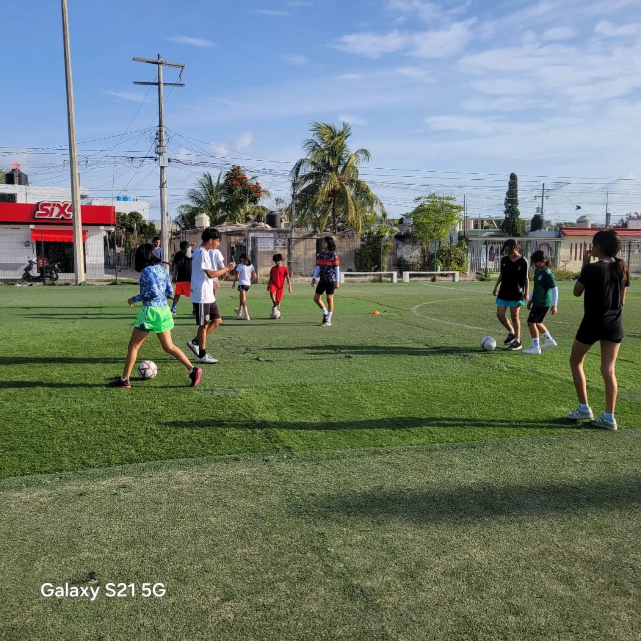 Un grupo de niñas y niños conduce balones durante un ejercicio de entrenamiento.