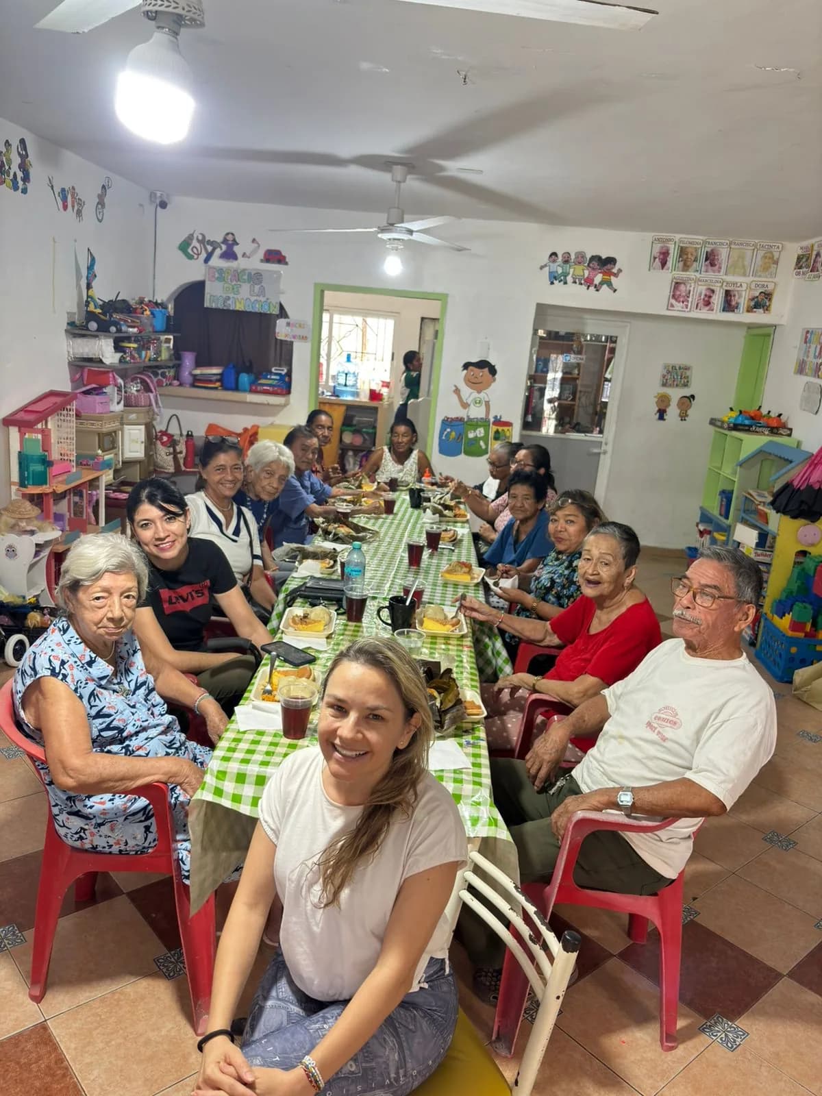 Personas adultas mayores comparten una comida alrededor de una mesa larga.