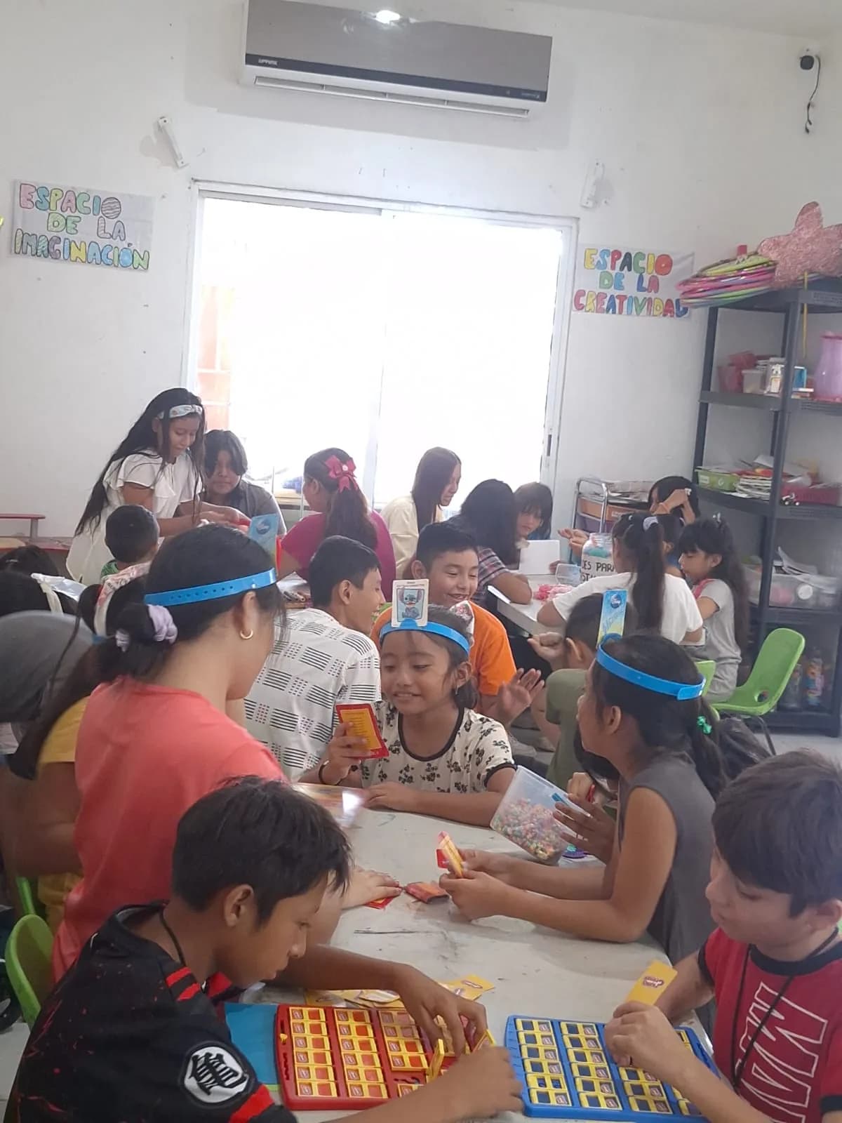 Niñas y niños juegan por equipos con tableros y cartas en el espacio de la imaginación.