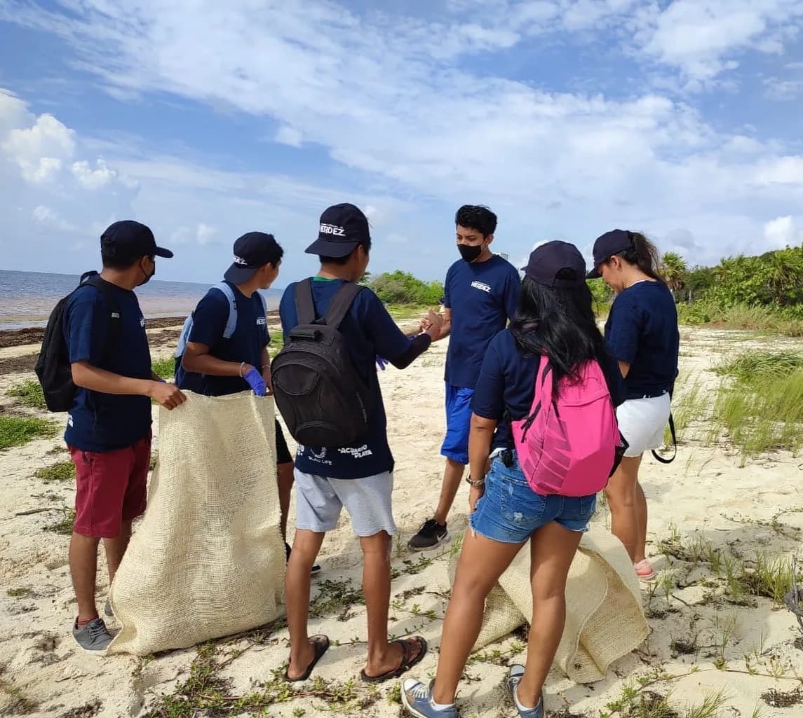 Un grupo de voluntarios organiza los costales antes de recorrer la costa recogiendo residuos.