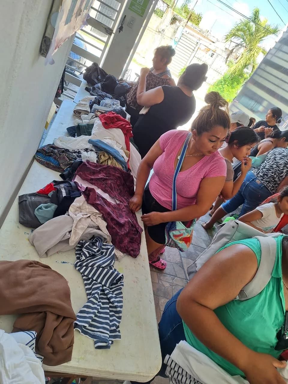 Vecinas revisan la ropa extendida sobre las mesas del bazar comunitario.