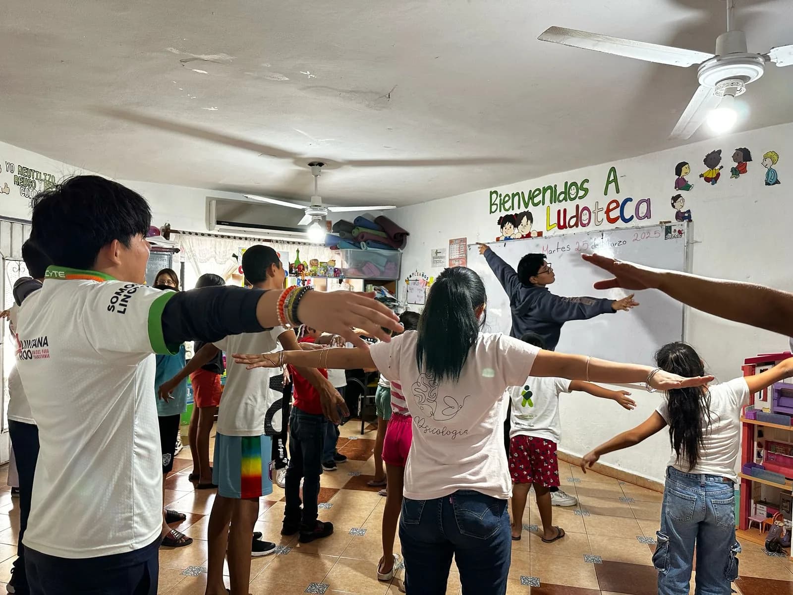 Voluntarios guían una activación física con niñas y niños en la ludoteca.